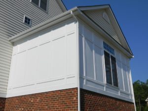 White paneled sunroom with brick foundation