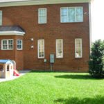 Brick townhouse yard with green lawn, playhouse