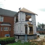 Home addition under construction with worker on roof