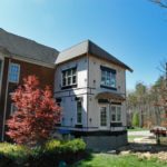 Two-story house with bay windows and red tree