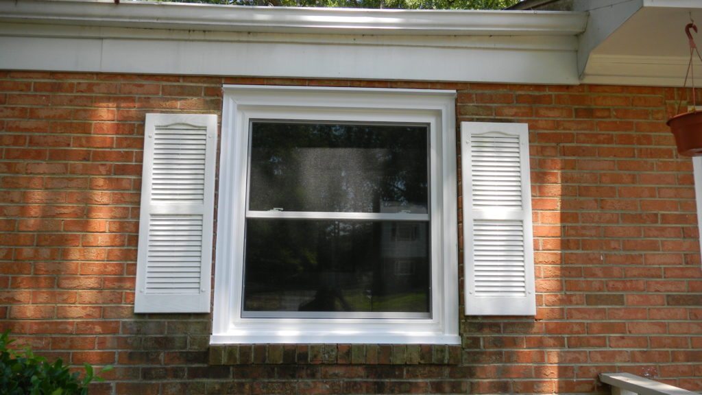 Brick house window with white shutters